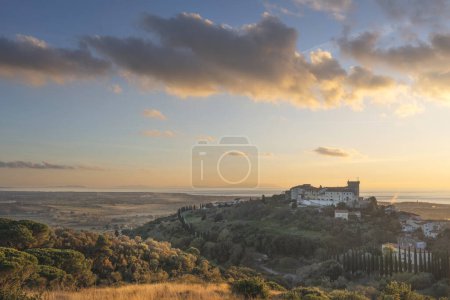 Téléchargez les photos : Vue d'en haut de la ville de Rosignano Marittimo et du château. Mer en arrière-plan au coucher du soleil. Région Toscane, Italie - en image libre de droit