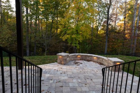 Photo for Picturesque backyard view in autumn season with patio pavers and stone wall, autumn leaves, and colorful woods in the background. - Royalty Free Image