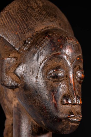 Eine afrikanische Frauenstatue, in Holz geschnitzt, isoliert auf schwarz. Traditionelle afrikanische Kunst mit ausgewogenen Formen und Volumen und schöner dunkelbrauner Patina.