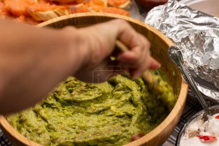 Mixing freshy homemade guacamole in a wooden bowl. Party catering concept.
