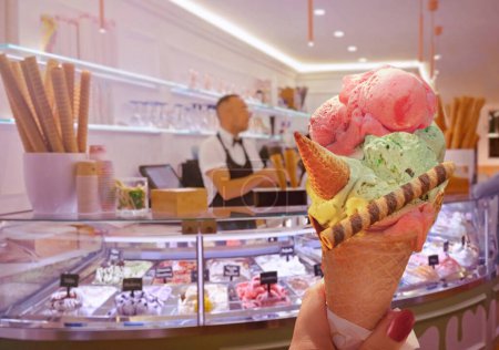 Foto de Helado italiano - cono de helado celebrado en la mano en el fondo de la tienda en Roma, Italia. Es uno de los mejores helados de la ciudad popular entre los turistas - Imagen libre de derechos