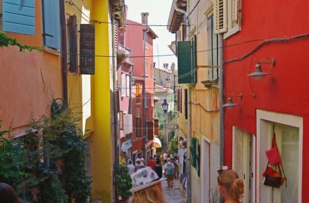 Téléchargez les photos : People walking in the street next to souvenir shops and sightseeing the souvenirs displayed on the walls of the buildings  in Rovinj, Croatia. Rovinj is a tourist destination on Adriatic coast of Croatia - en image libre de droit