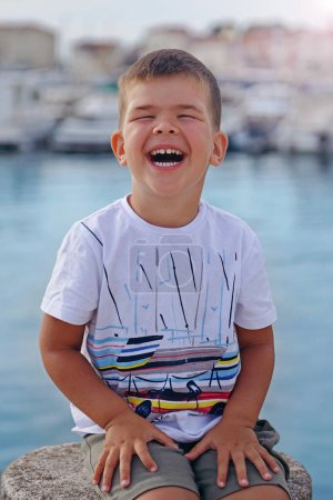 Photo for A portrait of a cute little boy who laughs on a warm summer day. Concept of summer holidays at sea and live style - Royalty Free Image