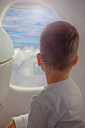 Foto de Vista posterior de niño pequeño que mira vista aérea del cielo y la nube fuera de la ventana del aeroplano. - Imagen libre de derechos
