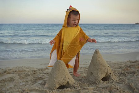 Téléchargez les photos : Little boy playing on beach and making sand castles.Child in nature with beautiful sea, sand and blue sky.Happy lifestyle childhood concept. - en image libre de droit