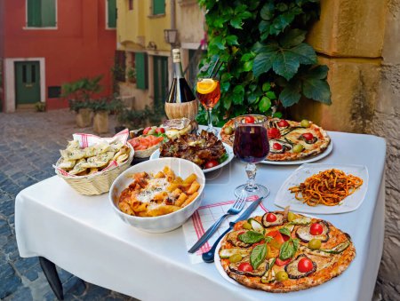 Photo for A summer  dinner.Traditional italian food in outdoor restaurant in Trastevere district.Tasty and authentic Italian kitchen.Pasta, pizza  and homemade food arrangement  in Rome, Italy - Royalty Free Image