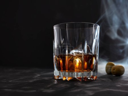 Téléchargez les photos : Verre à whisky sur un comptoir de bar avec fumée et olives. photo basse clé - en image libre de droit
