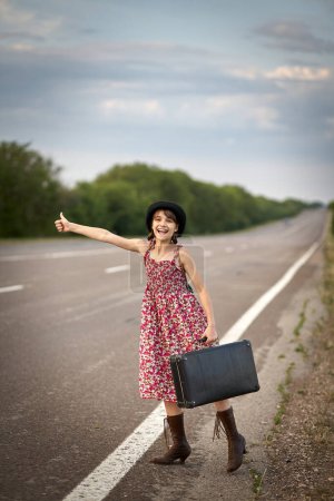 Photo for Girl on the road with old suitcase stoped auto - Royalty Free Image