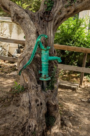 Téléchargez les photos : Old hand water pump on a well in the garden, watering and saving water, rural environnement. - en image libre de droit