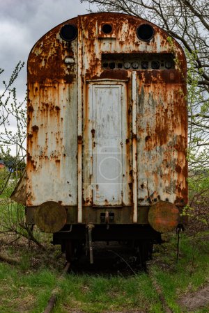 Téléchargez les photos : Vieux wagon de fret rouillé abandonné sur une voie ferrée avec de l'herbe verte - en image libre de droit