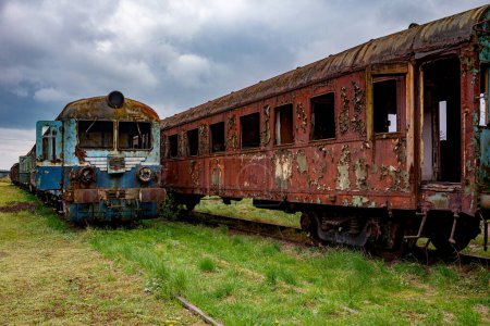 Téléchargez les photos : Ancienne UEM endommagée et voiture rouillée abandonnée sur une voie d'évitement ferroviaire sur un champ d'herbe verte - en image libre de droit