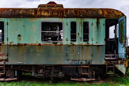 Téléchargez les photos : Ancien train-bloc électrique rouillé déclassé et abandonné sur la voie d'évitement du chemin de fer sur un champ herbeux vert - en image libre de droit