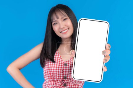 Photo for Beautiful Asian young woman ,Excited surprised girl showing big smart phone with blank screen , white screen for Mobile App Advertising isolated on blue background , smart phone display Mock Up Image - Royalty Free Image