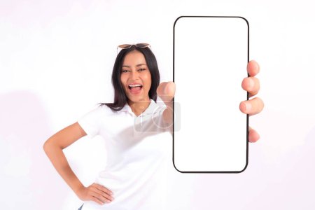 Photo for Beautiful Asian brunette woman cute girl in white shirt  ,Excited surprised girl showing big smart phone with blank screen , white screen isolated on white background , Display Mock Up Image - Royalty Free Image