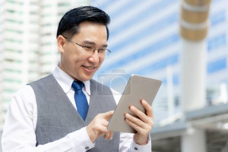 Foto de Hombre asiático de negocios utilizando tableta de ordenador en el distrito de negocios urbano - estilo de vida concepto de gente de negocios - Imagen libre de derechos
