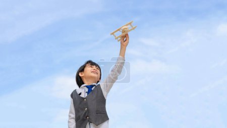 Téléchargez les photos : Mignon asiatique petit garçon jouant aviateur jouet avion imagination rêvant d'être un avenir pilote sur fond de ciel bleu Liberté et enfants rêve concept - en image libre de droit