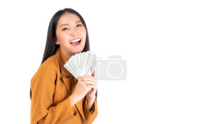 Téléchargez les photos : Succès belle entreprise asiatique jeune femme remplir heureux tenant de l'argent billets en dollars américains à la main isolé sur fond blanc, concept de réussite d'entreprise - en image libre de droit