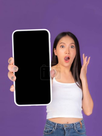 Photo for Beautiful Asian brunette woman cute girl in white tank top ,Excited surprised girl showing big smart phone with blank screen , black screen isolated purple background , Mock Up Image - Royalty Free Image