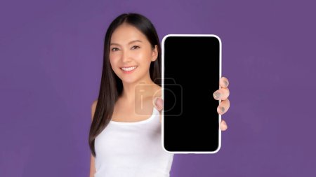 Téléchargez les photos : Belle asiatique jeune femme montrant grand téléphone intelligent avec écran blanc, écran blanc isolé sur fond violet, affichage maquette image - en image libre de droit
