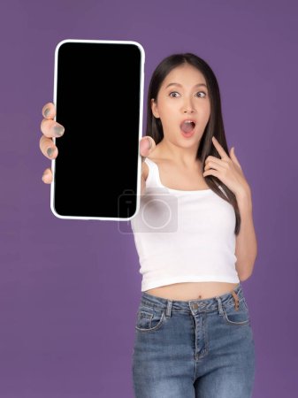 Téléchargez les photos : Belle asiatique jeune femme, excitée surprise fille montrant grand téléphone intelligent avec écran blanc, écran blanc isolé sur fond violet, affichage image maquillée - en image libre de droit