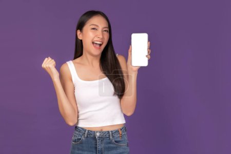 Photo for Portrait of beautiful Asian young woman showing smart phone with blank screen , white screen  empty copy space for advertising banner isolated on purple background , Mock Up Image - Royalty Free Image
