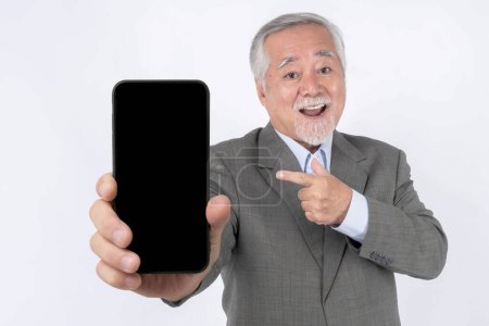 Téléchargez les photos : Asian senior businessman , old man with suit feel happy pointing finger to big smart phone with blank screen , white screen isolated on white background - smart phone empty display Mock Up Image - en image libre de droit