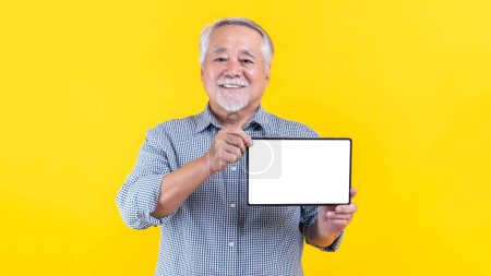 Foto de Asian senior man , old man showing smart phone , tablet phone computer with blank screen ,white screen ,empty copy space for advertising banner isolated on on yellow background , Mock Up Image - Imagen libre de derechos
