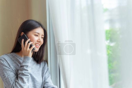 Téléchargez les photos : Lifestyle belle beauté femme asiatique mignonne fille se sentent heureux parler sur smartphone à meilleur ami dans la chambre à coucher à la maison - en image libre de droit