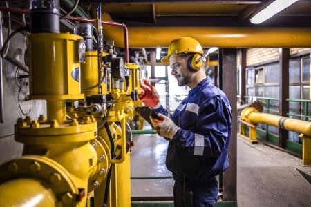 Téléchargez les photos : Refinery worker monitors and controls specialized equipment processing refine crude oil. - en image libre de droit