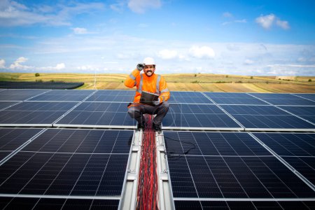 Solarenergiearbeiter oder Ingenieur mit seinem Laptop, der die Installation und Produktivität eines neuen Solarkraftwerks überprüft.