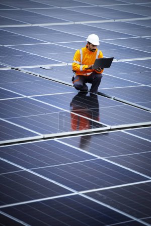 Téléchargez les photos : Travailleur professionnel avec ordinateur portable contrôlant la production d'électricité de la centrale solaire. - en image libre de droit