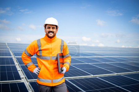 Portrait of solar panel worker standing inside sustainable energy power plant.