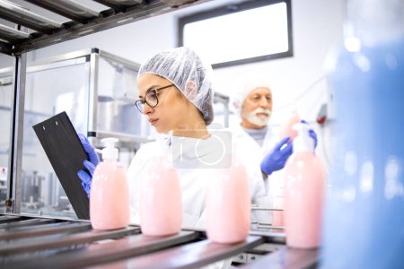 Factory workers or technologists controlling process of shampoo production.