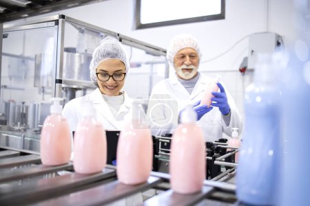 Foto de Producción de cosméticos y trabajadores en espera de la máquina haciendo control de calidad de productos químicos de limpieza. - Imagen libre de derechos