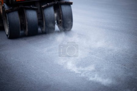 Photo for Road construction and pneumatic tire roller machine for asphalt paving. New layer of asphalt vaporize. - Royalty Free Image