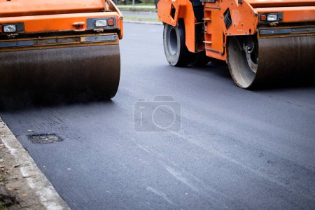 Photo for Road construction machinery in action and asphalt paving machine making new layer flat and smooth. - Royalty Free Image