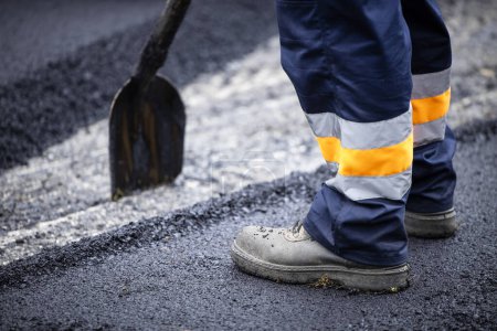 Photo for Road construction or reparation and worker with shovel spreading new layer of asphalt. - Royalty Free Image