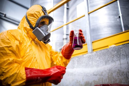Photo for Worker in hazmat suit and gas mask checking PH level of chemicals and acids for industry. - Royalty Free Image