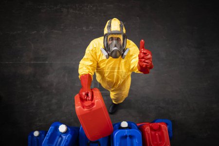 Téléchargez les photos : Travailleur professionnel en combinaison de protection contre les dangers et masque à gaz travaillant avec des produits chimiques dangereux à l'intérieur de l'usine. - en image libre de droit