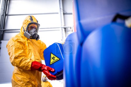 Téléchargez les photos : Travailleur d'usine avec masque à gaz et combinaison de protection travaillant avec des produits chimiques toxiques et dangereux. - en image libre de droit