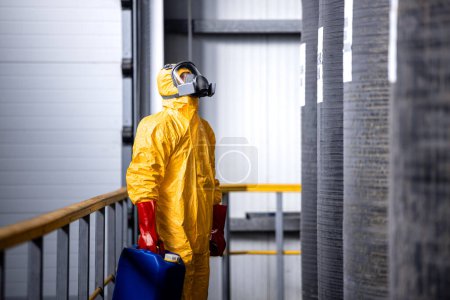 Téléchargez les photos : Ouvrier d'usine en équipement de protection vérifiant la quantité de produits chimiques à l'intérieur du grand réservoir. - en image libre de droit
