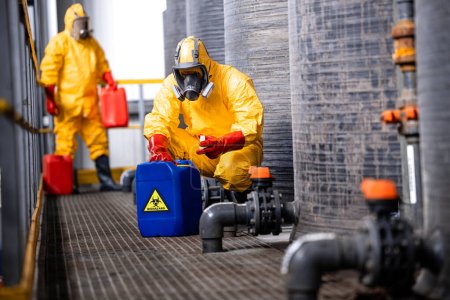 Travailleurs d'usine formés manipulant soigneusement les déchets toxiques et dangereux dans une usine chimique.