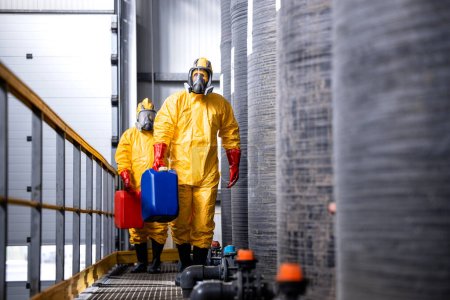Trabajadores totalmente protegidos en traje amarillo, máscaras antigás y guantes que manipulan sustancias o productos químicos peligrosos.