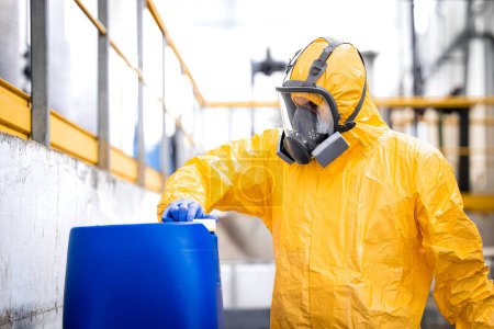 Téléchargez les photos : Worker wearing protection equipment and gas mask working in chemicals production factory. - en image libre de droit