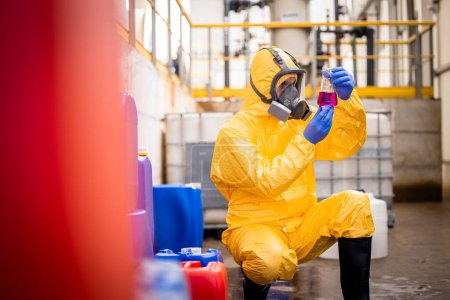 Téléchargez les photos : Travailleur de contrôle de qualité en combinaison de protection et masque à gaz testant la qualité des produits chimiques à l'intérieur de l'usine de production chimique . - en image libre de droit