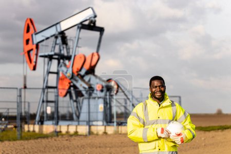 Photo for Portrait of an oil field worker standing in front of the oil rig. - Royalty Free Image