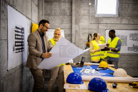 Photo for Team of structural engineers and architects analyzing plans and blueprints at construction site. - Royalty Free Image