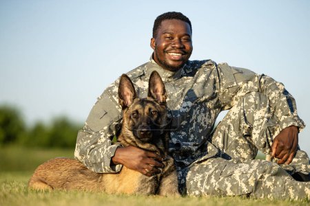 Retrato de soldado sonriente y perro militar mirando directamente a la cámara.