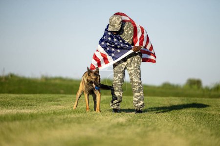 USA marine soldier standing by his military dog and holding flag.
