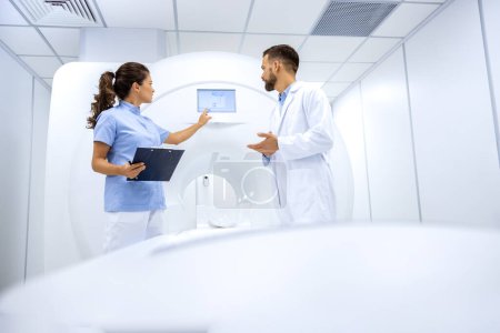 Médecin radiologue et technicienne préparant une IRM en salle d'examen médical.